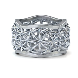 Può includere: Un anello d'argento con un design delicato e intricato di stelle intrecciate. L'anello è largo e ha una forma leggermente curva.