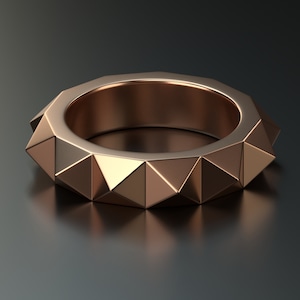 May include: A rose gold ring with a geometric design. The ring is made of multiple triangular shapes that create a unique and modern look.