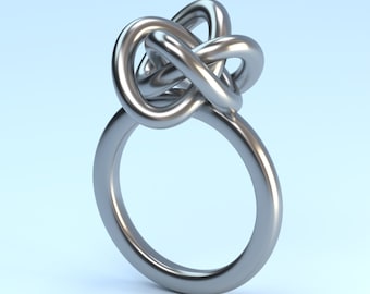 Puede incluir: Un anillo de plata con un diseño de nudo. El nudo es un patrón complejo e entrelazado que crea un aspecto único y llamativo.
