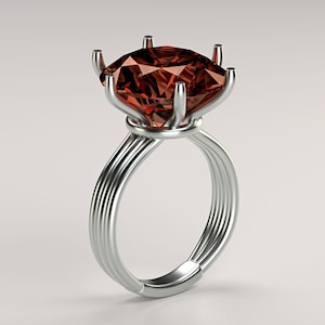 May include: A silver ring with a large, faceted, reddish-brown gemstone. The ring's band is composed of multiple parallel strands, and the gemstone is held in place by six prongs.