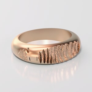 May include: A rose gold ring with a textured, carved design on one side. The ring has a smooth, rounded band and a detailed, organic pattern that adds visual interest. The ring is displayed on a white surface.
