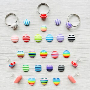 Peut inclure: Assortiment d'anneaux et de boucles d'oreilles rayés de couleurs vives. Les anneaux sont en argent et les boucles d'oreilles sont en argent avec une tige. Les boucles d'oreilles sont de formes variées, notamment des cercles, des carrés et des cœurs.