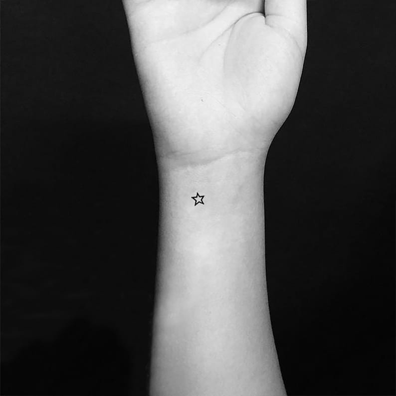 May include: A small, simple star tattoo on a person's wrist.