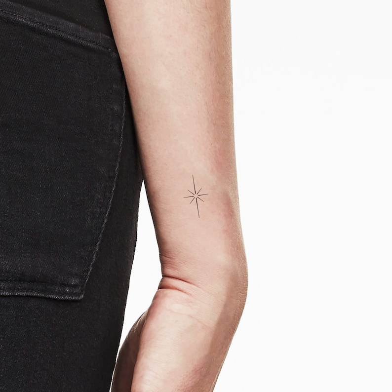 K&ouml;nnte beinhalten: Ein einfaches schwarzes Stern-Tattoo auf dem Arm einer Person.