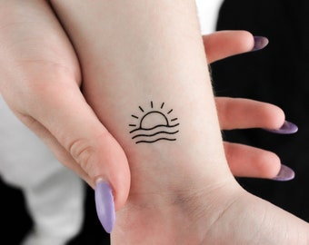 Puede incluir: Un tatuaje sencillo de línea de un sol poniéndose sobre el océano en la muñeca de una persona.