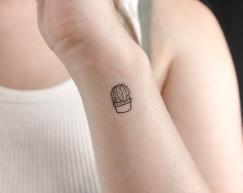 May include: A small black line drawing of a potted cactus on a person's wrist.
