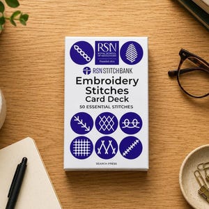 May include: A white rectangular card deck box titled RSN Stitchbank Embroidery Stitches Card Deck 50 Essential Stitches. The box features blue circular icons displaying various embroidery stitch patterns and the Royal School of Needlework logo.