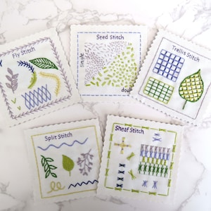 May include: Five white fabric squares with different embroidery stitches. Each square has a title: Fly Stitch, Seed Stitch, Trellis Stitch, Split Stitch, and Sheaf Stitch. The stitches are done in shades of green, blue, and purple.