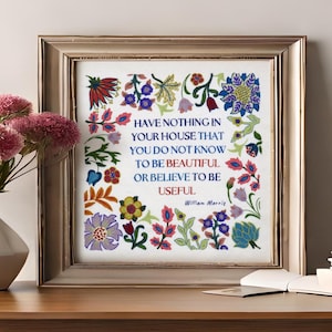 Op de afbeelding: Een ingelijst kunstwerk met een citaat van William Morris, omringd door kleurrijke bloemenborduurwerk. Het citaat luidt: "Heb niets in je huis waarvan je niet weet dat het mooi is of waarvan je gelooft dat het nuttig is."