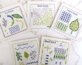 May include: Five white fabric squares with different embroidery stitches. Each square has a title: Fly Stitch, Seed Stitch, Trellis Stitch, Split Stitch, and Sheaf Stitch. The stitches are done in shades of green, blue, and purple.