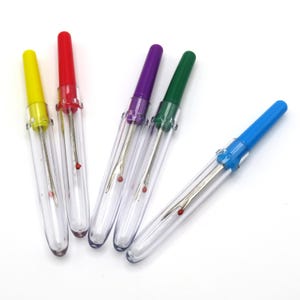 May include: Five colorful threader tools with clear plastic bodies and red tips. The threaders are yellow, red, purple, green, and blue.