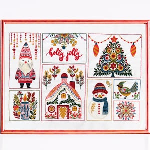 May include: A white embroidery hoop with a red frame, featuring a Christmas-themed design. The design includes a gnome, a house, a snowman, a bird, a candle, a tree, and the words "holly jolly".
