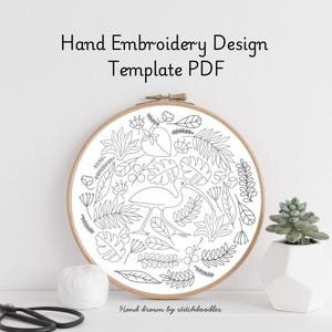 Peut inclure: Un modèle PDF de broderie à la main. Le motif représente un oiseau entouré de diverses feuilles et fleurs, le tout en noir. Le motif est placé dans un cercle à broder en bois. Le texte sur l'image indique "Hand Embroidery Design Template PDF" et "Hand drawn by stitchdoodles."