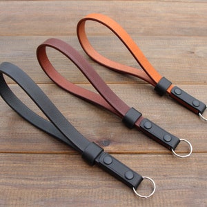 May include: Three leather keychains with metal rings. The keychains are black, brown, and orange.