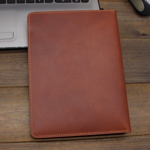 May include: A brown leather laptop sleeve with a stitched edge.