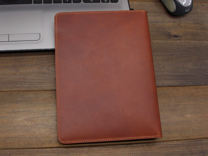 May include: A brown leather laptop sleeve with a stitched edge.