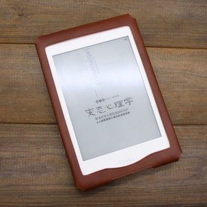 May include: A brown leather case for an e-reader with a white screen displaying the text "(ab)normal" and "変心心理学".