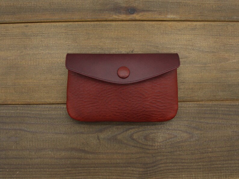 Puede incluir: Una peque&ntilde;a cartera de monedas de cuero rojo con cierre de bot&oacute;n.