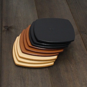 Puede incluir: Un conjunto de siete posavasos de cuero en varios tonos de marr&oacute;n, beige y negro. Los posavasos est&aacute;n dispuestos en forma de abanico, con el posavasos negro en la parte superior.