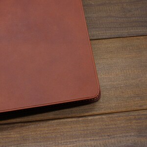 May include: A brown leather notebook cover with a stitched edge.