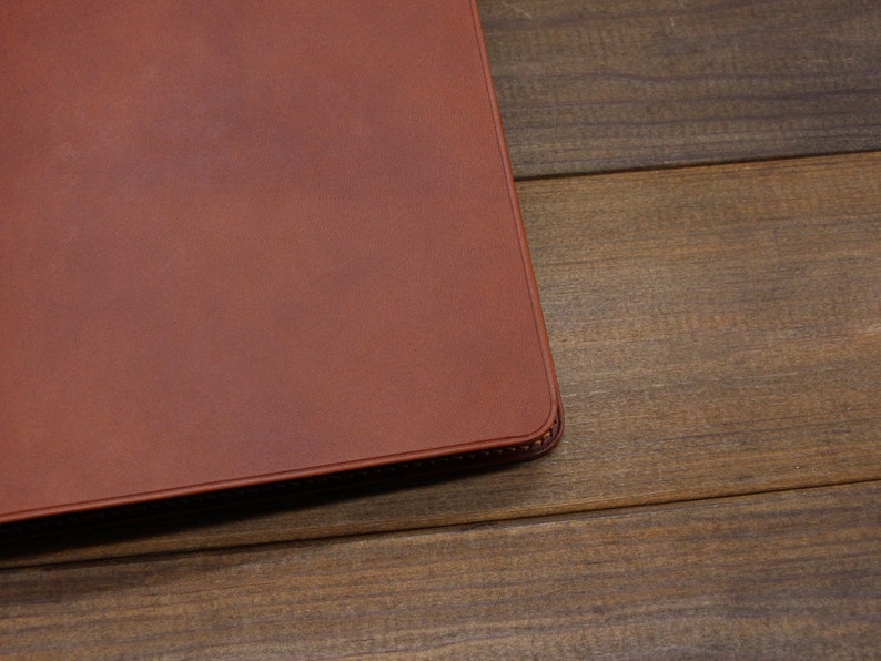 May include: A brown leather notebook cover with a stitched edge.
