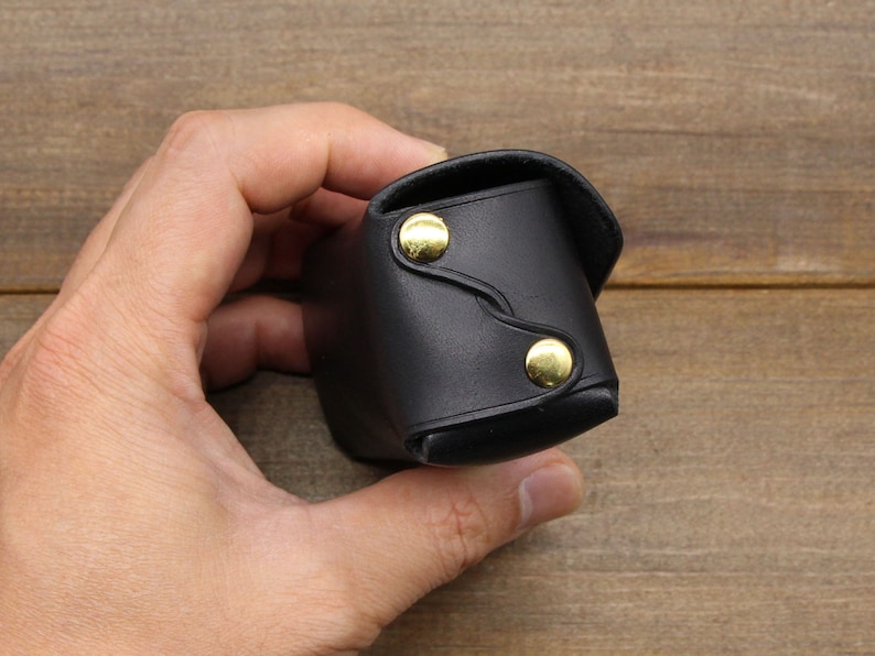 May include: A black leather case with gold accents. The case is closed and has a flap.