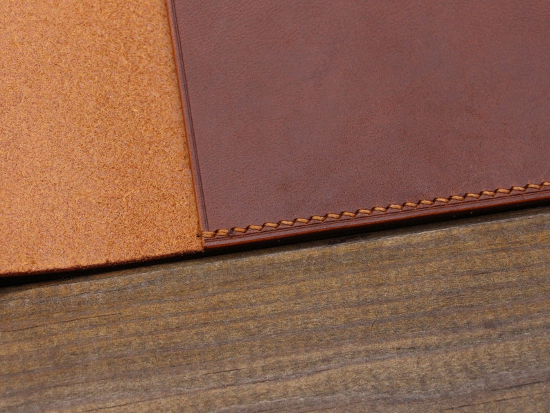 May include: Close-up of two pieces of brown leather stitched together with a decorative stitch. The leather is smooth and has a natural grain.