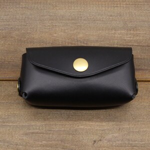 May include: A black leather key holder with a gold button closure.