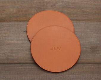 May include: Two brown leather coasters with the initials "BLW" embossed on one of the coasters.