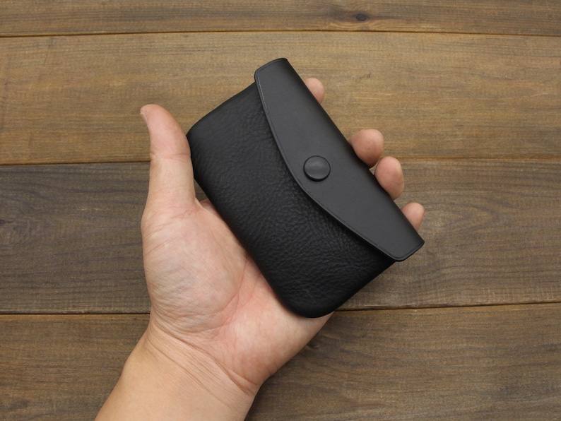 Puede incluir: Una peque&ntilde;a cartera de monedas de cuero negro con cierre de presi&oacute;n. La cartera es peque&ntilde;a y compacta, lo que la hace ideal para llevar efectivo o monedas.