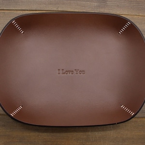 May include: A brown leather tray with stitched edges and the text "I Love You" embossed in the center.