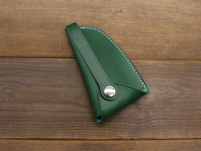 May include: A green leather key holder with white stitching and a silver button.