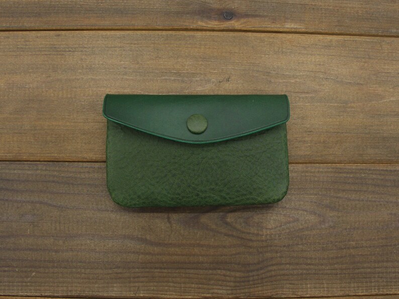 Puede incluir: Una peque&ntilde;a cartera de monedas de cuero verde con cierre de bot&oacute;n.