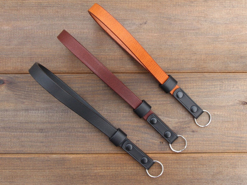 Pu&ograve; includere: Tre portachiavi in ​​pelle con anelli metallici neri e bottoni neri. I portachiavi sono marroni, marrone scuro e neri.