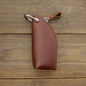 May include: A brown leather key chain with a silver ring and a brown leather strap.