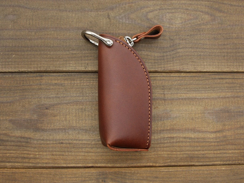 May include: A brown leather key chain with a silver ring and a brown leather strap.