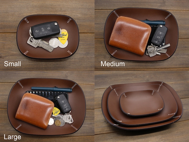 May include: Three leather trays in different sizes: small, medium, and large. The trays are brown and have a stitched edge. The small tray has a key and a few coins in it. The medium tray has a brown leather wallet and keys. The large tray has a brown leather wallet, keys, and a pen.