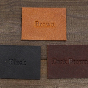 May include: Three leather swatches, one brown, one black, and one dark brown. The swatches are labeled with their respective colors.