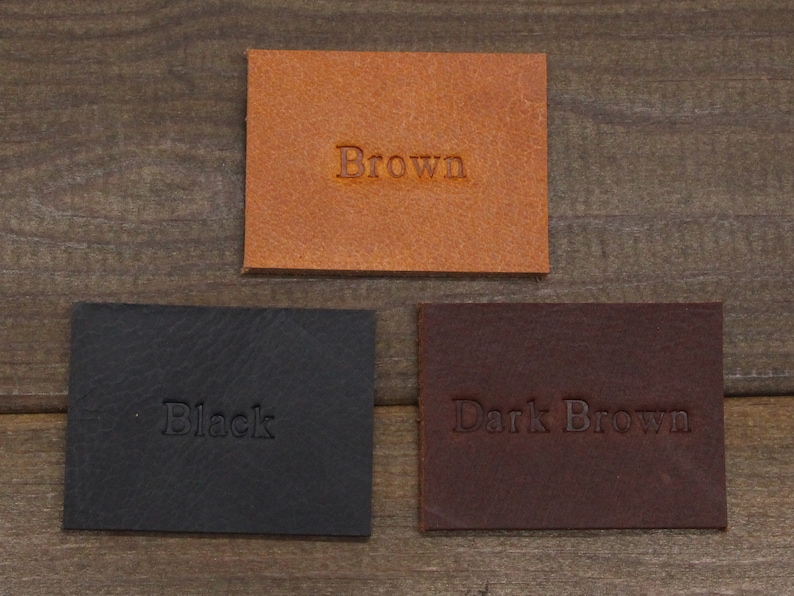May include: Three leather swatches, one brown, one black, and one dark brown. The swatches are labeled with their respective colors.
