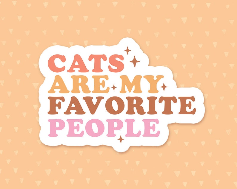 May include: A white sticker with the text "Cats are my favorite people" in colorful, retro-style lettering. The text is in pink, orange, yellow, and brown. There are small stars around the text.