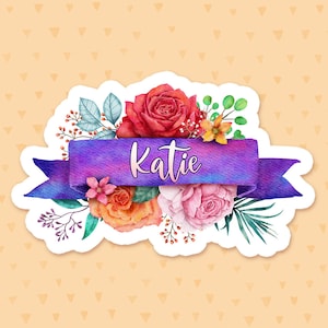 May include: A purple watercolor ribbon with the name "Katie" written in white script. The ribbon is surrounded by a bouquet of watercolor flowers in shades of red, orange, pink, and yellow.