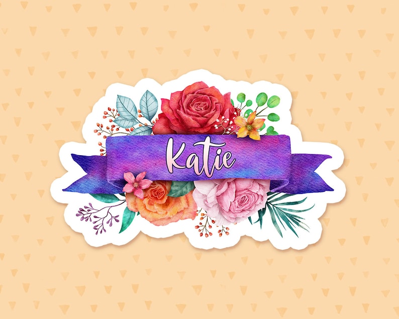 May include: A purple watercolor ribbon with the name "Katie" written in white script. The ribbon is surrounded by a bouquet of watercolor flowers in shades of red, orange, pink, and yellow.