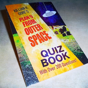 May include: A yellow, green, and purple book cover with the title "Killian H. Gore's Plan 9 From Outer Space Quiz Book" and the text "With Over 200 Questions!"
