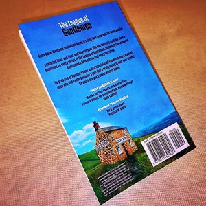 May include: The back cover of a book titled "The League of Gentlemen". The cover features a blue sky with white clouds and a small stone building with a sign that reads "Local Shop". The text on the cover describes the book as a series of questions and answers, including a quiz, and includes praise for the book from John Landis and Killian R. Gore.