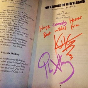 May include: A book titled "The League of Gentlemen: Unauthorised Quiz Book" by Killian H. Gore and Phoenix Hinkley. The book has a handwritten message that says "Huge Comedy Horror Best wishes from" and is signed by "K.H.G." in red and "P.H." in purple.