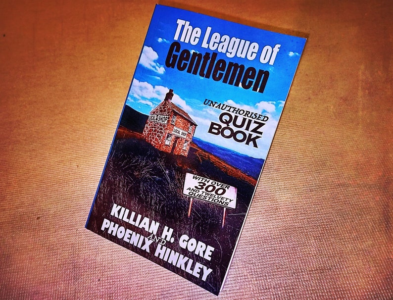 May include: A book titled "The League of Gentlemen Unauthorised Quiz Book" with a blue sky and a stone building on the cover. The book has over 300 questions and is written by Killian H. Gore and Phoenix Hinkley.