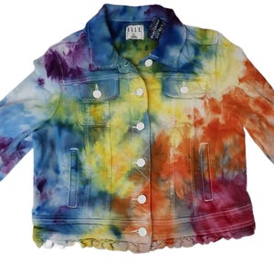 May include: A tie-dye denim jacket in a rainbow of colors, including purple, blue, yellow, orange, and red. The jacket has a classic design with a collar, button-up front, and pockets. The brand tag reads "ELLE".