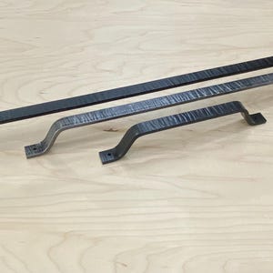 May include: Three black metal drawer pulls of varying sizes. The pulls have a hammered finish and a curved shape.