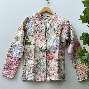 May include: A patchwork quilted jacket featuring a range of colours and patterns, including pink, blue, green, and brown. The jacket has a mandarin collar and a button fastening.