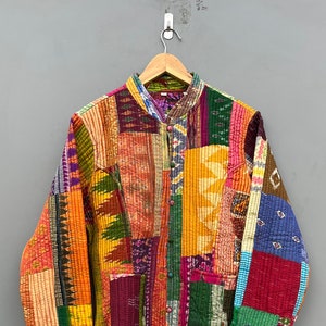 May include: A colourful patchwork quilted jacket with a mandarin collar and button fastening. The jacket is made from various fabrics in shades of red, orange, yellow, green, blue and purple.